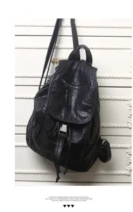 Close-up detail of the black soft leather backpack showing zipper pocket and metal clasp.