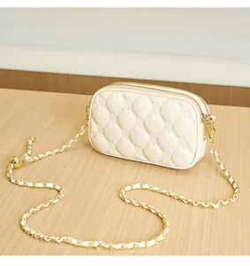 Chic white quilted crossbody bag with gold chain strap, stylish compact shoulder bag.