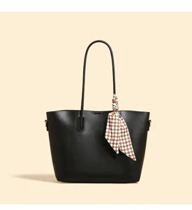 Black tote bag detail featuring premium leather texture and chic checkered scarf accessory.