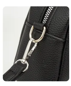 Close up of black leather handbag metal hardware zipper and strap buckle detail.