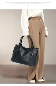 Vintage leather tote bag detail showing dual top handles, side buckles and premium hardware.