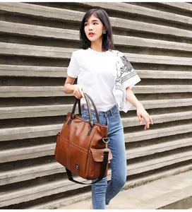 Detail view of the retro brown tote bag with double handles, worn by model in urban street style.