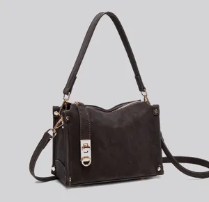 Nahaufnahme der dunkelbraunen Wildleder-Achseltasche mit Metallverschluss und Reißverschluss.