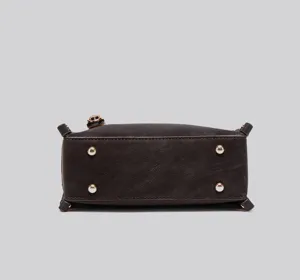 Nahaufnahme der Unterseite der dunkelbraunen weichen Handtasche mit Metallfüßchen.