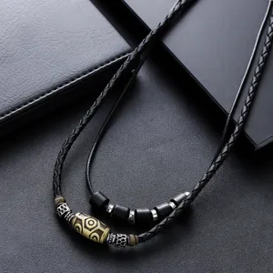 Collana vintage con perla Dzi nera intrecciata e ciondoli in metallo etnico, scatto di dettaglio.