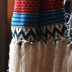 Detailaufnahme eines boho-ethnischen Strickschals mit geometrischen Mustern und Fransen.