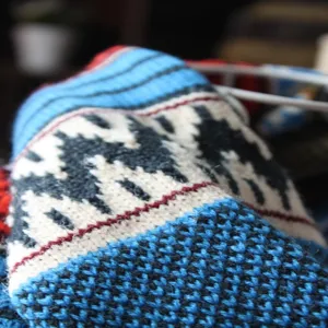 Nahaufnahme eines bohemischen Strickschals mit geometrischen Mustern in Blau, Schwarz und Rot.