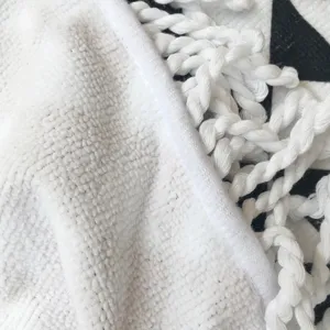 Close-up detail van zachte ronde strandlaken stof textuur en elegante witte franjes.
