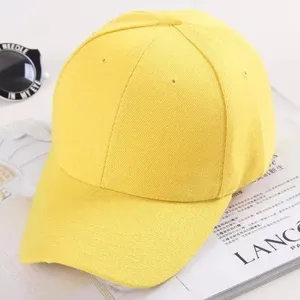 Detail de casquette de baseball jaune montrant le tissu uni et la visiere courbee.