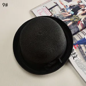 Close-up detail of black straw hat showing fine woven texture and black ribbon bow.