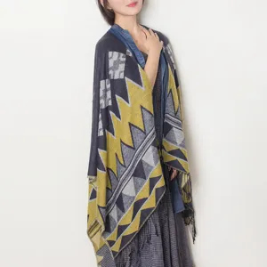 Women knit tassel cape shawl detail view, geometric pattern winter warm clothing accessory.