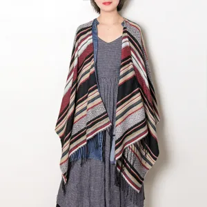Detailed view of the geometric patterned knitted poncho with fringe hem, soft and warm texture.