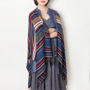 Detail shot of the blue geometric patterned fringe shawl cape, showcasing texture and drape.