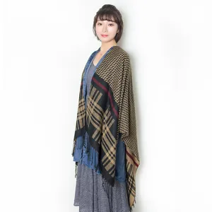 Close up view of the stylish plaid and chevron patterned tassel cape worn by the model.