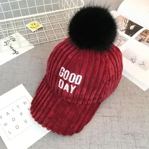 Detail view of winter thick corduroy baseball cap with cute black pom-pom and embroidery.