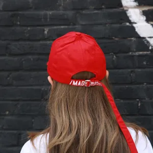 Detailed view of red baseball cap with long strap and warning text, streetwear style.