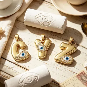 Close-up detail of 18K gold-plated alphabet pendants featuring exquisite evil eye rhinestone design.