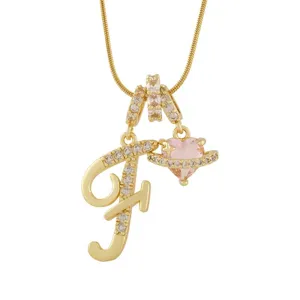 Gros plan détaillé du collier pendentif lettre F plaqué or avec un charm cœur en cristal rose.