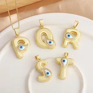 Detail view of 18K gold plated evil eye letter pendants with sparkling stones, perfect for DIY jewelry.