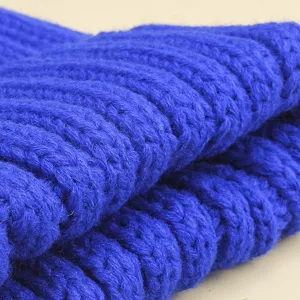 Gros plan sur la texture du bonnet en tricot côtelé bleu roi pour enfants en hiver.