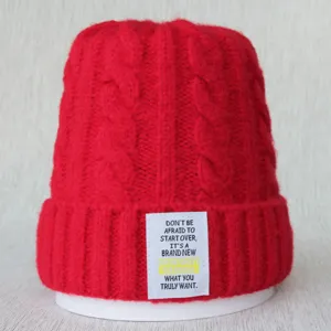 Bonnet tricoté rouge motif torsade hiver avec détail d'étiquette de texte anglais.