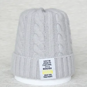 Vue détaillée du bonnet en tricot gris avec un patch tissé de citation anglaise.