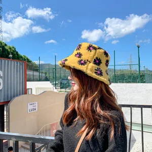 Cozy fuzzy yellow bucket hat with black floral pattern, soft warm winter plush hat detail.