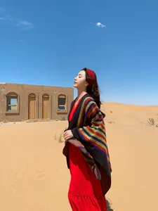 Outdoor desert scene showcasing a colorful striped ethnic poncho worn with a red dress, detail shot.