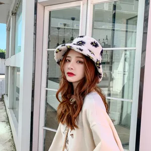 Close-up detail of a cute fuzzy winter bucket hat with daisy print, soft cozy warm headwear.