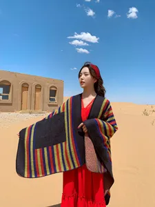 Detail view of a colorful striped ethnic shawl worn in desert backdrop, warm autumn style cape.