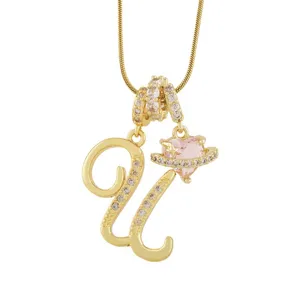 Gros plan détaillé d'un collier pendentif lettre plaqué or avec un charm cœur saturne rose étincelant.