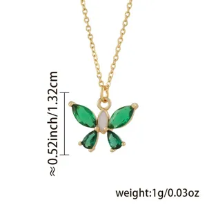 Detailaufnahme einer filigranen Gold Schmetterling Kette mit grünen Kristallen und weißem Körper.