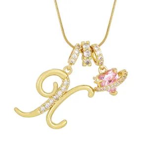 Vue rapprochée détaillée de la lettre plaquée or et du pendentif cœur planète rose scintillant.