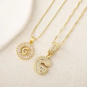 Vista detallada de collares con colgante de letra G chapados en oro con circonitas.