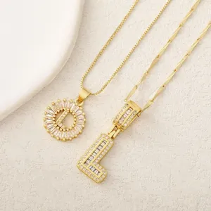 Primer plano detallado de exquisitos collares con letras de cristal chapadas en oro.