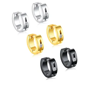 Detalle de pendientes de aro huggie de acero inoxidable con pedrería en tres colores.