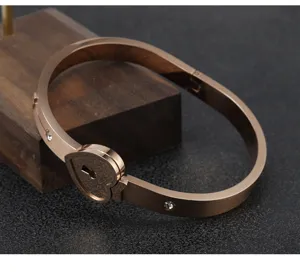 Primer plano de detalle del brazalete con cierre de corazón en acero inoxidable dorado.