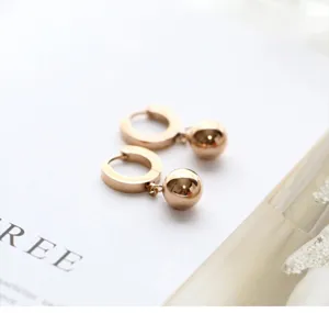 Close-up of elegant gold stainless steel ball drop earrings featuring a minimalist hoop design.