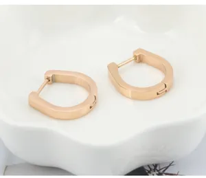 Primer plano detallado de pendientes de aro ovalados y lisos en elegante oro rosa.