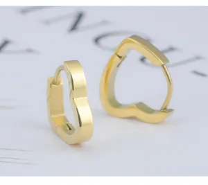Nahaufnahme von minimalistischen goldenen Herz Creolen Ohrringen aus glattem Edelstahl.