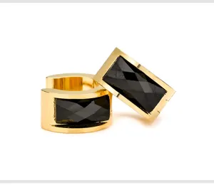 Close-up detail of geometric gold-plated stainless steel earrings with black faceted stone.