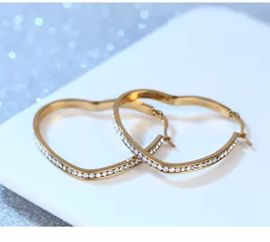 Boucles d'oreilles créoles coeur en acier titane doré avec strass brillants pour femmes.