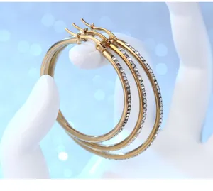 Close-up detail of stylish gold hoop earrings half paved with sparkling rhinestones.