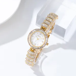 Detailed view of women luxury diamond gold quartz watch with elegant mother of pearl dial.