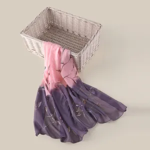 Vista dettagliata della sciarpa in seta sfumata rosa e viola con delicati motivi di rami.