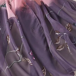Primo piano di sciarpa donna rosa e viola con elegante stampa di rami e farfalle.