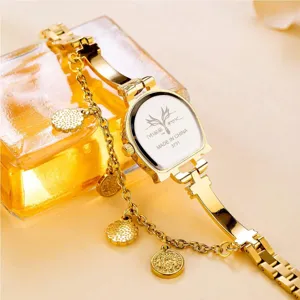 Gold women's quartz watch detail, unique U-shaped strap with chic charm pendants and clear dial.