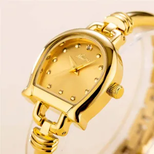 Close-up detail shot of luxury gold horseshoe quartz women watch dial and metallic bracelet.