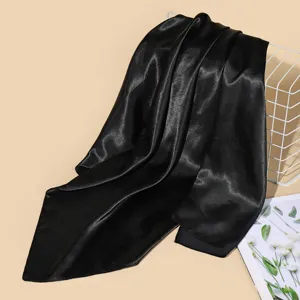 Close-up detail shot of a smooth black satin square scarf draped gracefully on wire basket.