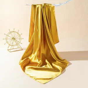Golden satin silk scarf detail showing smooth texture and elegant drape for summer fashion.